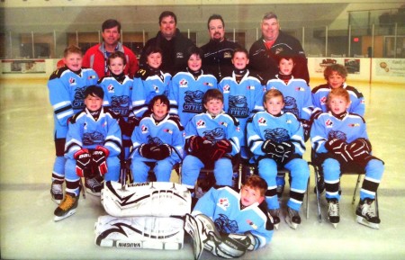 A posed photo of a youth hockey team and their coaches.