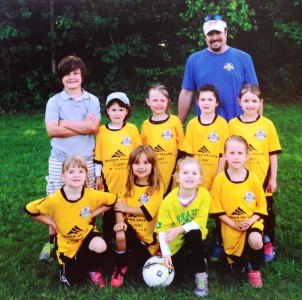 A posed photos of a youth soccer team and their coach.