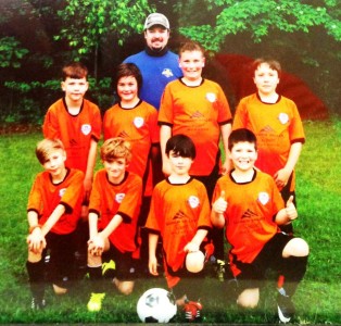 A posed photo of a youth soccer team and their coach.