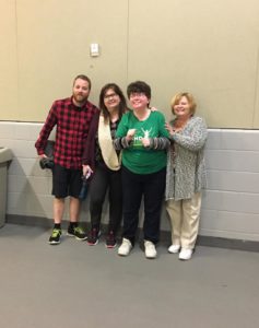 A man and three women pose for a photo on an indoor walking track.