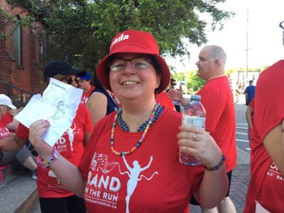 A woman in a red hat and red Band on the Run T-shirt smiles for the camera.
