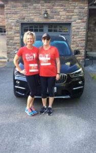 Two people in Band on the Run T-shirts pose for a photo in front of a black car.