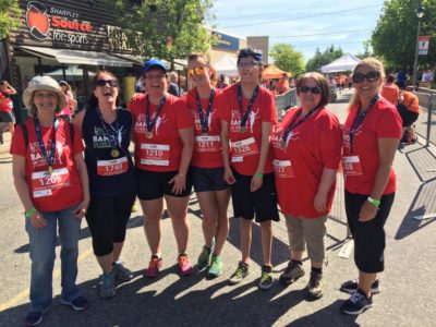 Seven people in Band on the Run T-shirts smile for the camera. They all have finisher medals draped around their necks.