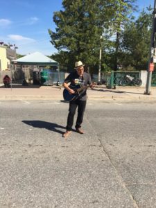 A man plays a guitar along the race route.