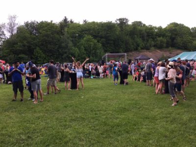 Hundreds of people gather in a park after the race during a music festival.