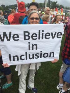 A woman holding a sign that reads: We Believe in Inclusion