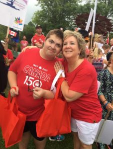 A woman in a red T-shirt and white shorts puts her arms around the shoulders of a man wearing a red-and-white Canada 150 T-shirt