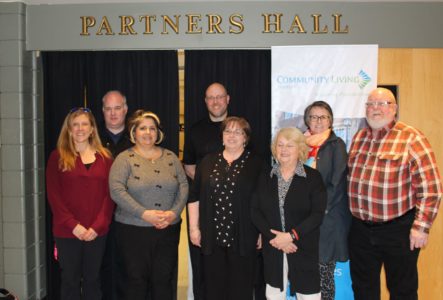 Image shows seven people standing inside the Huntsville Civic Centre under a sign that reads: Partners Hall. 