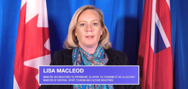 Image shows a blonde woman at a podium with a blue curtain, Canada flag and Ontario flag behind her. Test reads: Lisa MacLeod, minister of heritage, sport, tourism and culture industries, in both French and English.