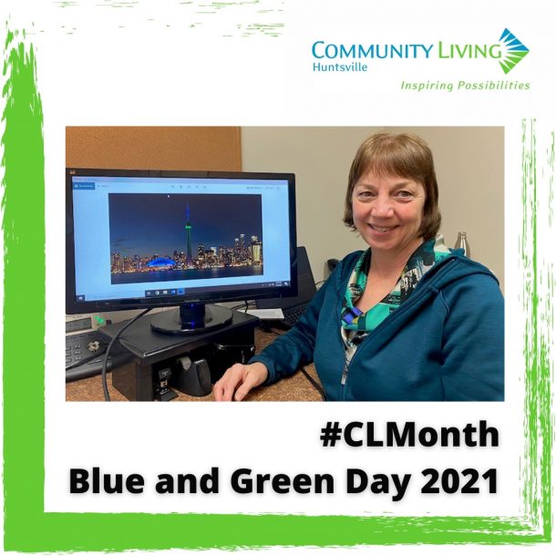 A woman in a green top in front of a computer that displays the CN tower lit in blue and green