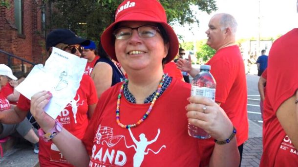 A smiling Band on the Run race participant in red shirt and red hat.