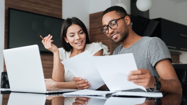 A stock photo of a smiling couple reviewing financial paperwork.