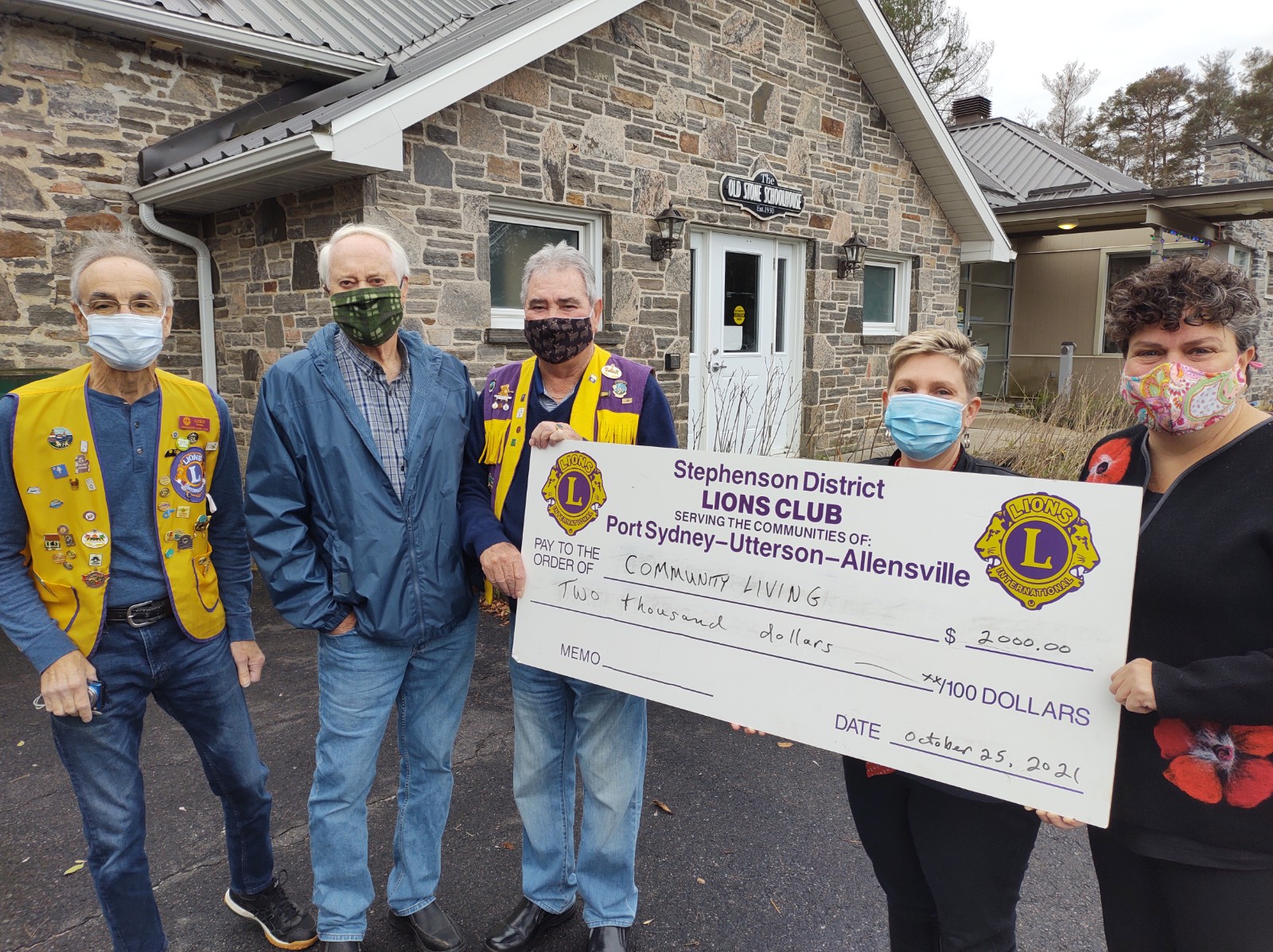 A photo of 3 Lions Club members presenting a giant novelty cheque with a $2,000 donation to 2 Community Living Huntsville staff.