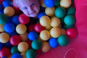 A child in a play bin of colourful plastic balls.