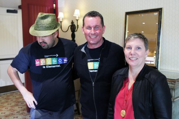 2 men and 1 woman smiling for the camera. The men wear shirts that read: Inclusion Is Elemental.