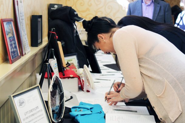 A woman writes on a silent auction bid sheet.