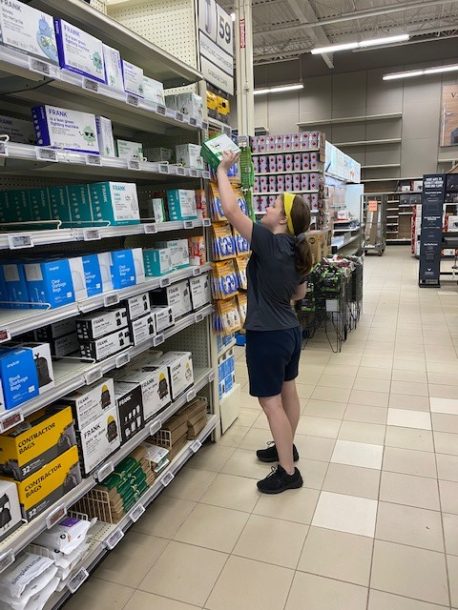 A young woman places a retail product on a store shelf.