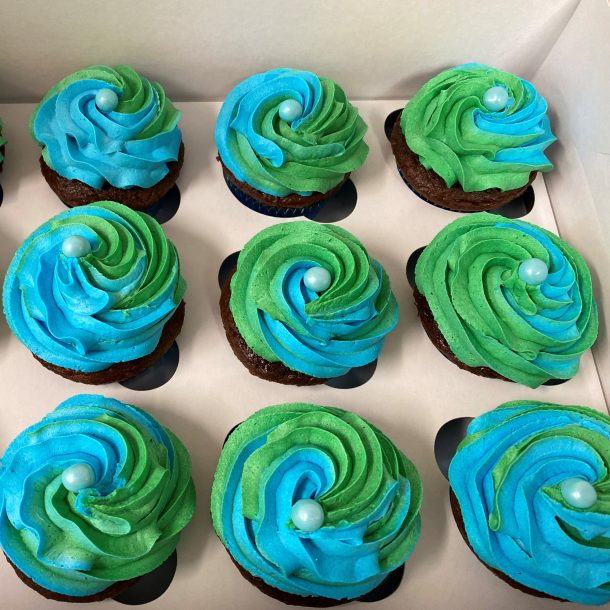 a box of cupcakes with blue and green icing.