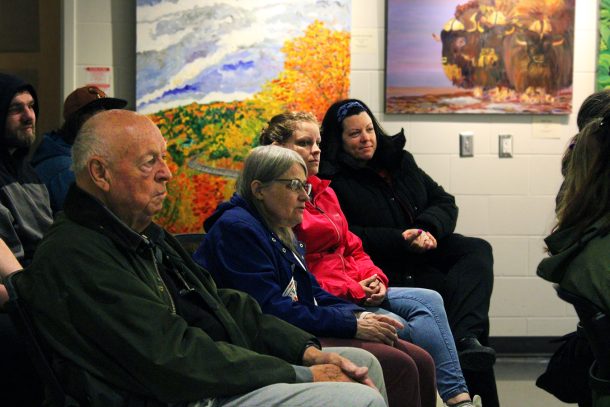 Four seated people look off camera toward an unseen speaker.