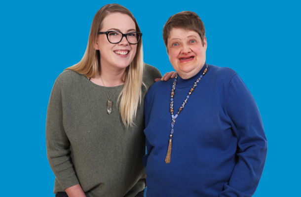 2 smiling women in front of a blue background