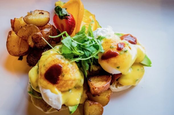 An overhead photo of a plate of eggs benedict and roasted potatoes.