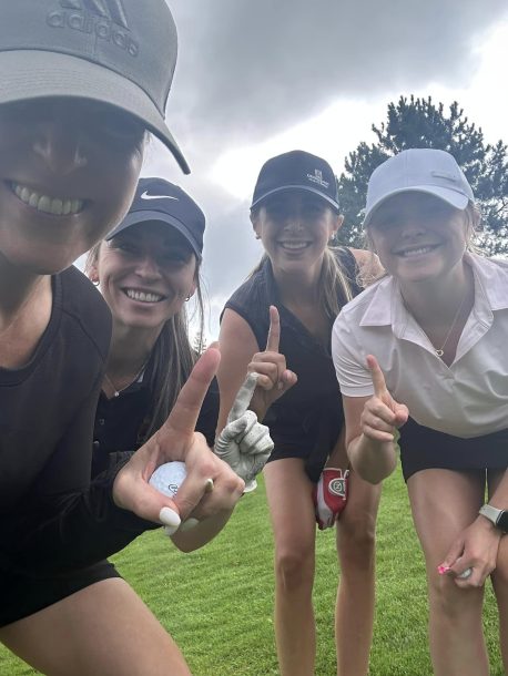 4 women snap a selfie while each person holds up their index finger as if to say "Number 1"