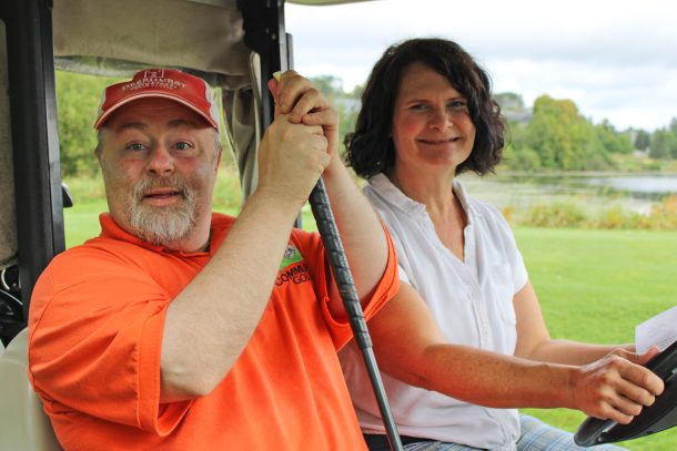 a smiling man and woman in a golf cart