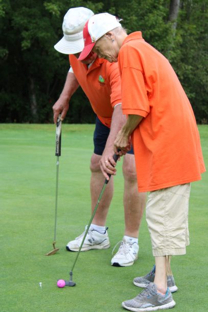 a man and a woman sink a putt on a golf green