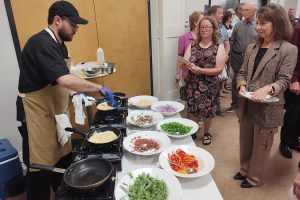 a man making omelets at an omelet station while diner watch.