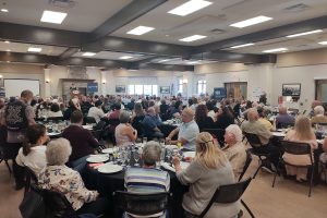 a large room filled with people seated at dining tables.