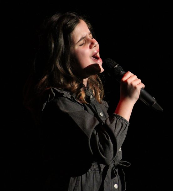 A young girl, Sadie, sings into a microphone.