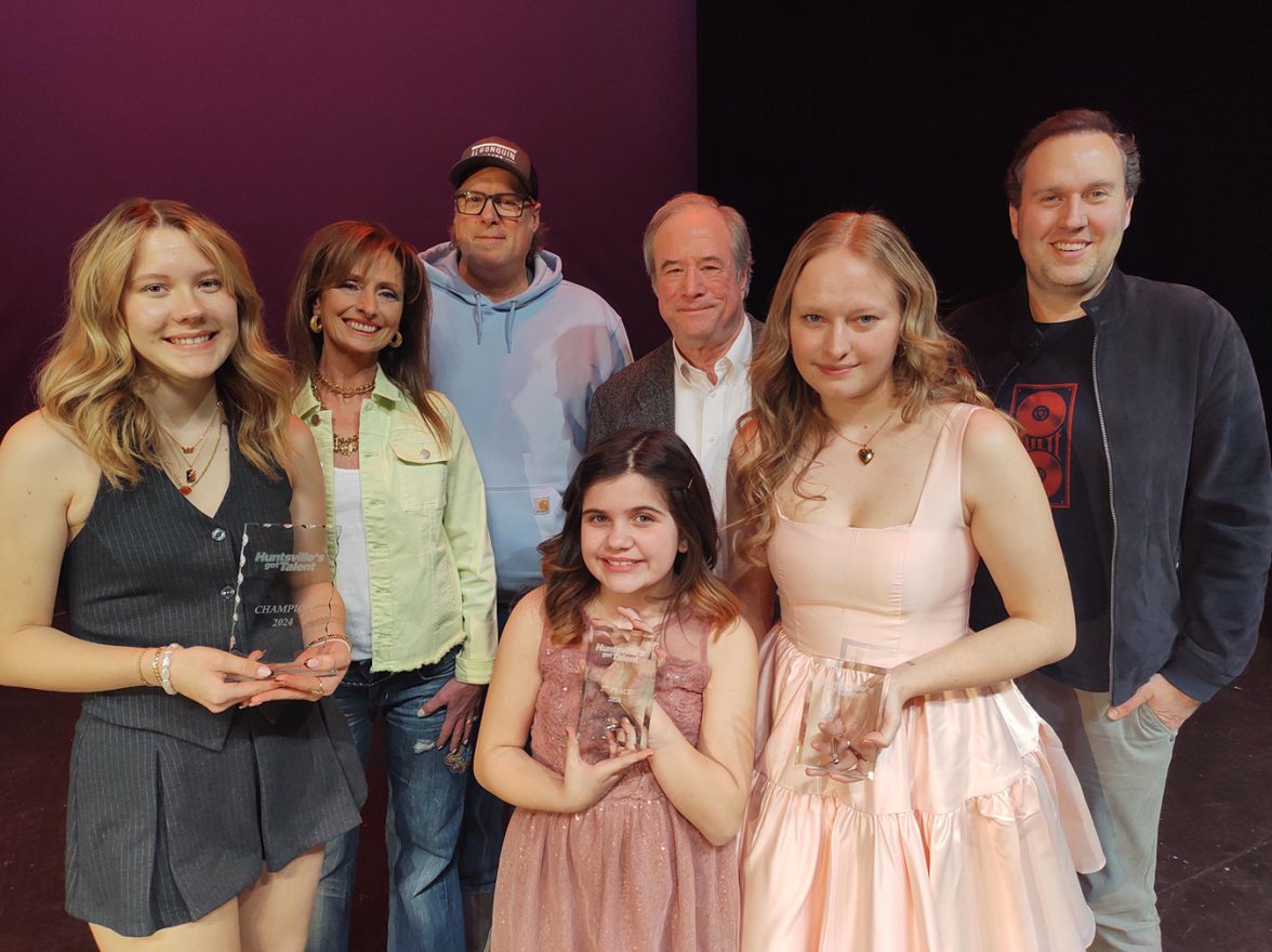 3 young women holding awards and 4 smiling people, the judges.