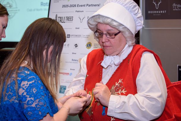 a young woman in a blue dress tries a key in a gold lock held by Mrs Claus