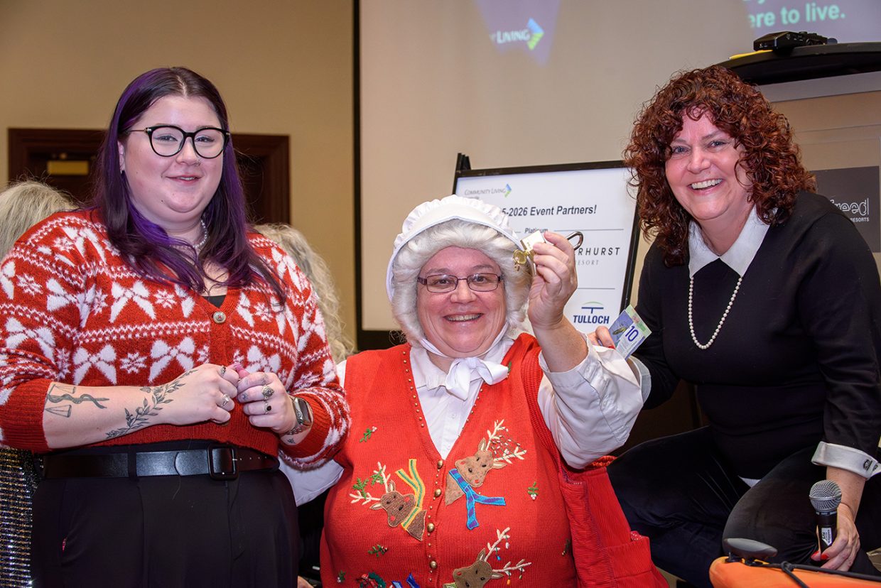 3 smiling woman, one of which is Mrs Claus holding up a winning key and lock