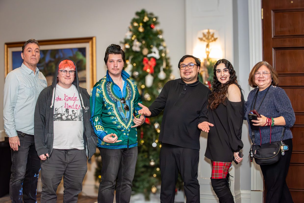 6 people, ASD Band, pose in front of a Christmas tree