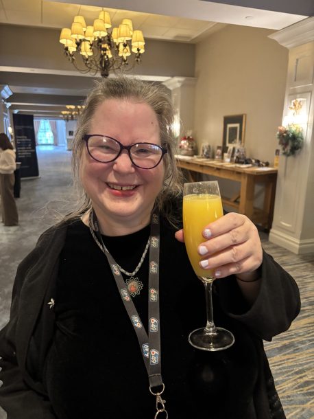 A smiling woman holds up a mimosa
