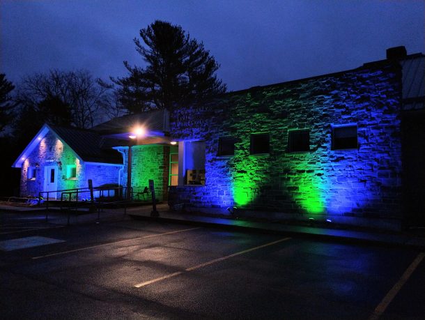 Community Living Huntsville's administration offices lit at dusk with blue and green floodlights.