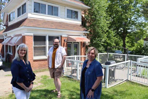 Diane, Chris, and Suzanne standing in front of a brick and siding-covered building, Floral Villa.