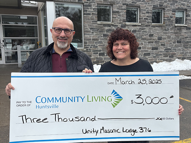 Man and woman holding large novelty cheque for $3,000 from Mason Lodge to Community Living Huntsville.
