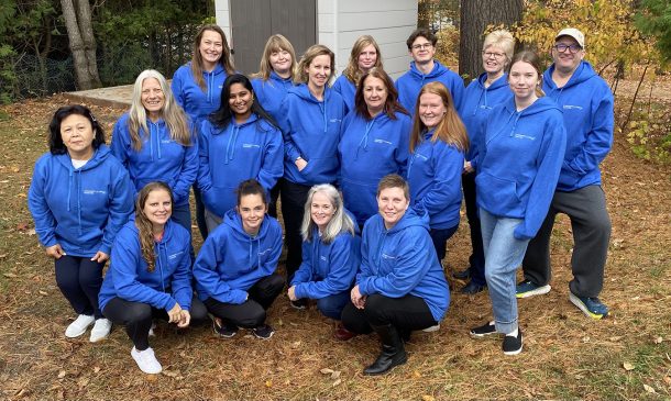 A group of employees in blue hoodie sweatshirts