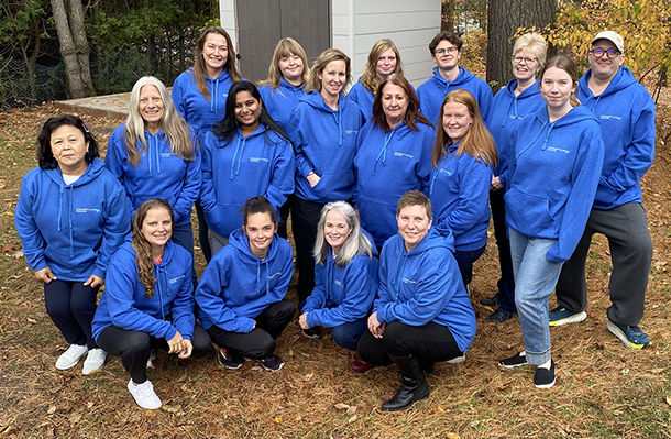 A group of employees wearing blue hooded sweatshirts.