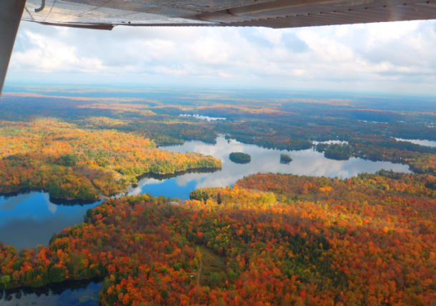 Aerial view of a chain of freshwater lakes surrounded by autumn trees with orange and red leaves.