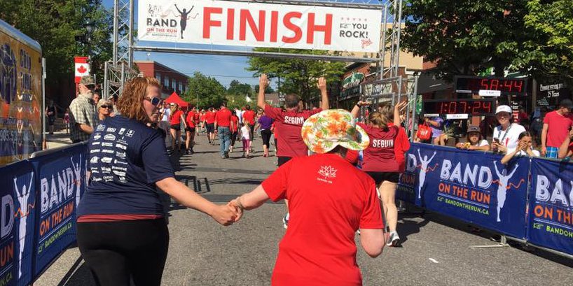 Two people holding hands while running toward a foot-race finish line